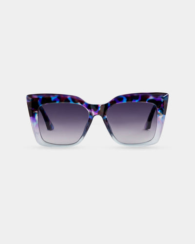 A pair of oversized cat-eye sunglasses featuring a bold blue and purple tortoiseshell frame with gradient lenses. The stylish design offers full eye coverage and a statement-making look.