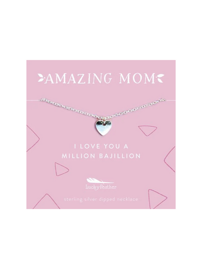 A silver heart necklace displayed on a pink card with the words "Amazing Mom" and "I love you a million bajillion." The necklace features a delicate chain and a small heart charm, perfect for gifting to a cherished mother.