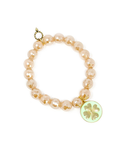 The Powerbeads by Jen bracelet features faceted gold iridescent quartz with light peach beads, a gold and pearl detail near the clasp, and a mint enameled shamrock charm on a round pendant set against a light green background.