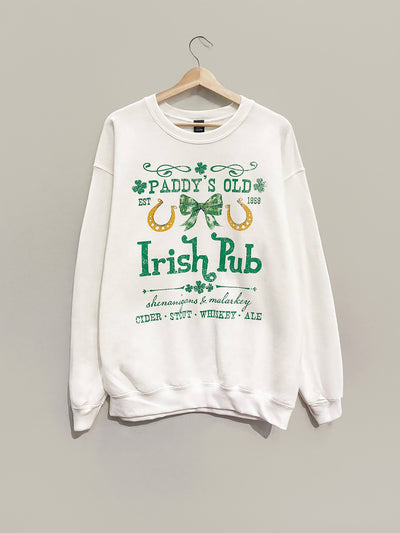 The Paddy's Old Irish Pub Oversized Sweatshirt in white features a vintage pub graphic with shamrocks, horseshoes, and a Celtic knot. It reads "Shenanigans & Malarkey," "Cider," "Stout," “Whiskey,” and “Ale.” Ideal for St. Patrick’s Day!.