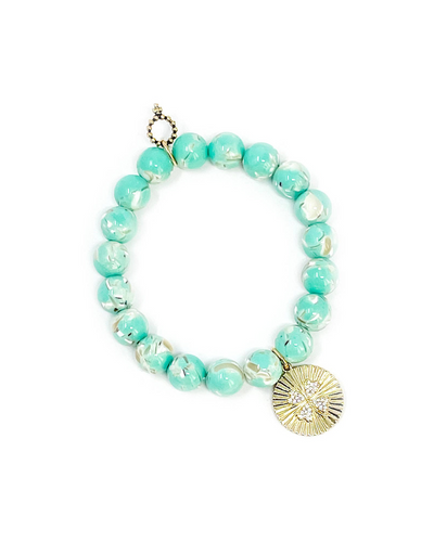 A Pistachio Mosiac Agate bracelet featuring a gold clover charm with crystal detail and a decorative toggle clasp.