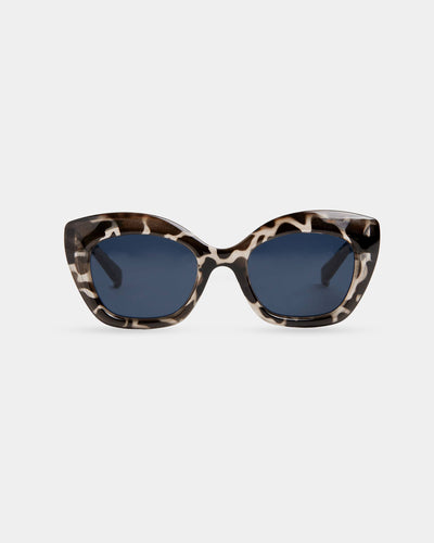 A pair of oversized cat-eye sunglasses with a black-and-white animal print frame and deep navy lenses.